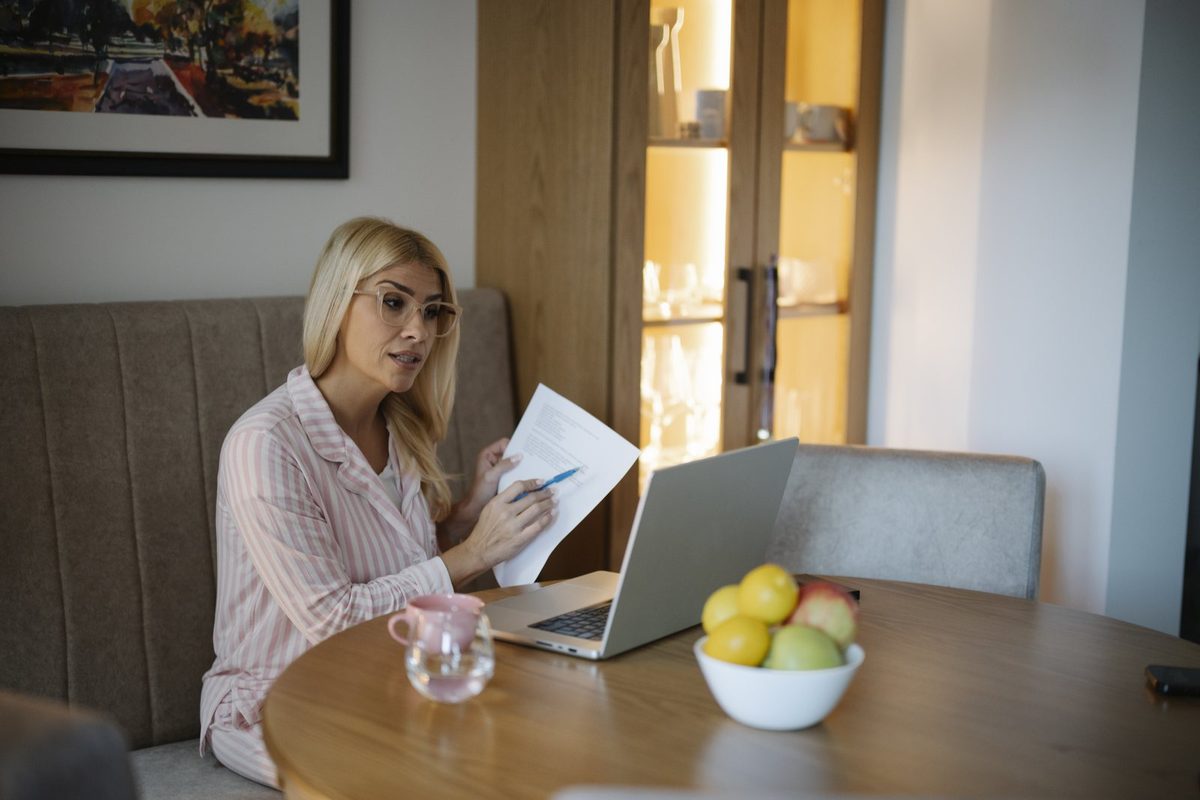 Homeowner comparing an online home value estimate on a tablet with an agent's printed comparative market analysis at a kitchen table