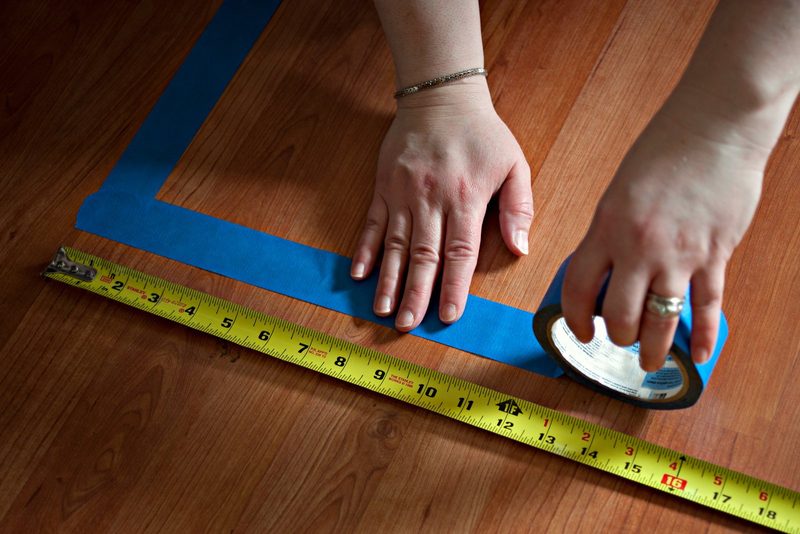 Tape measure stretched across the floor of an empty room in a house, checking the living area against the county property record