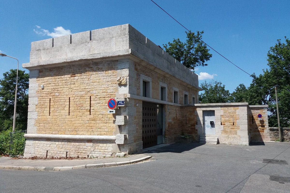 Detached stone house on a street corner in Lyon, France, with a flat roof and a dark wooden gate, the kind of home owners value online
