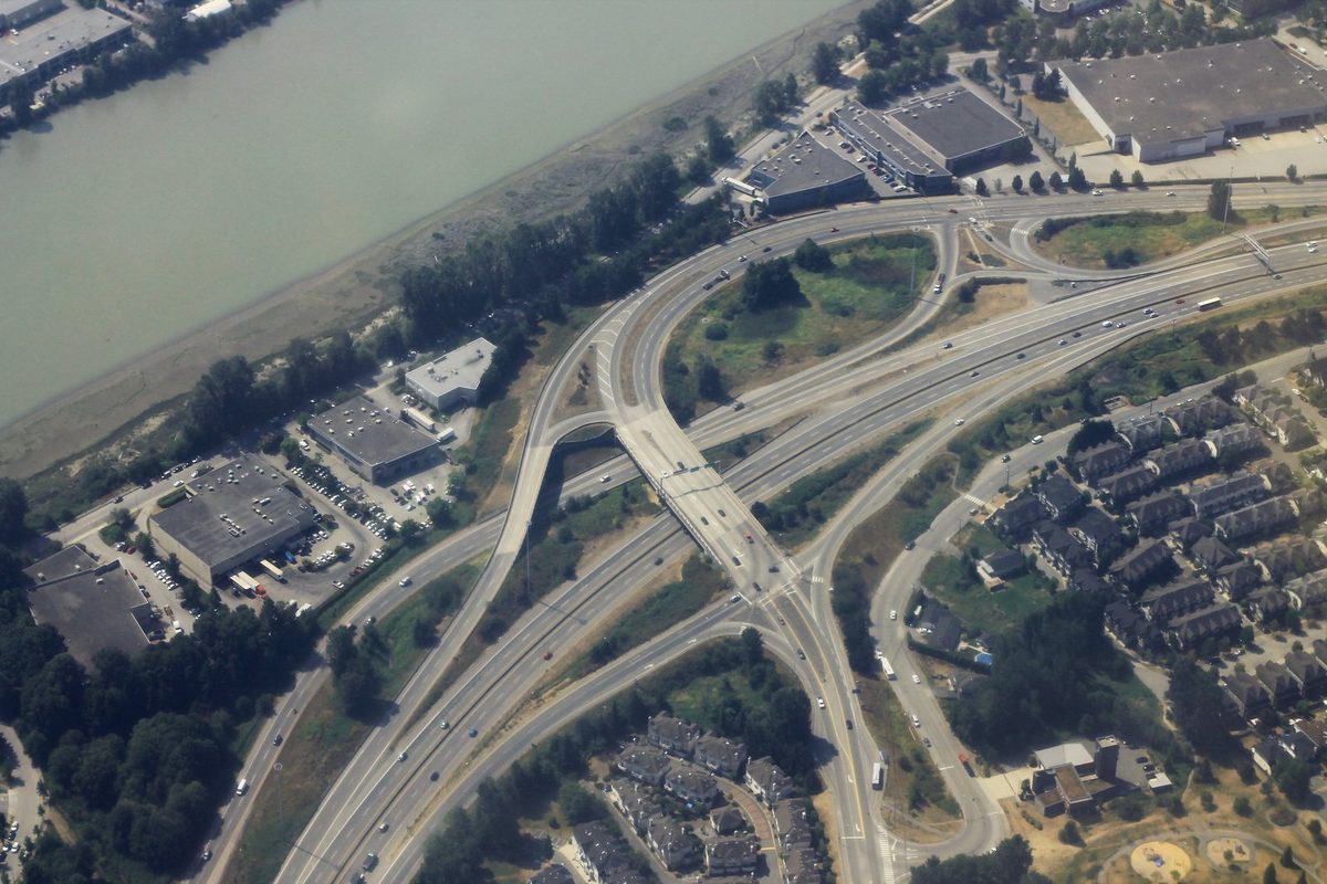 Single-family houses behind a concrete sound wall next to a multi-lane highway, the road noise that lowers property value