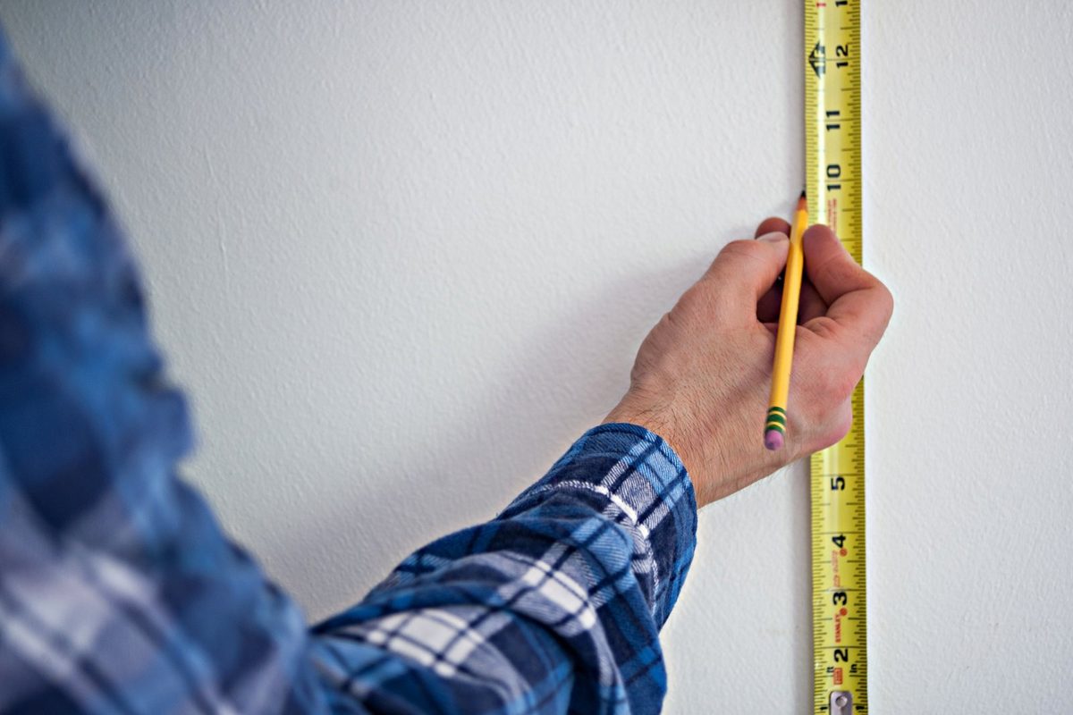 Maßband und Wohnungsgrundriss auf einem Tisch, Vorbereitung zum Berechnen des Quadratmeterpreises
