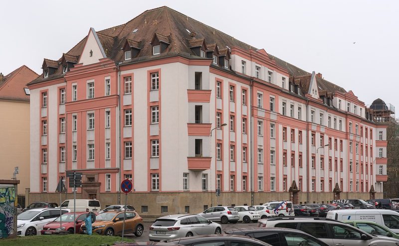 Mehrfamilienhaus in Leipzig mit rosa und weiß gegliederter Fassade, Dachgauben und parkenden Autos davor, typisches Objekt einer Mietpreisprüfung