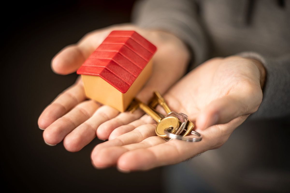 Übergabe eines Wohnungsschlüssels zwischen Vater und erwachsener Tochter vor einer Wohnungstür, Vermietung innerhalb der Familie