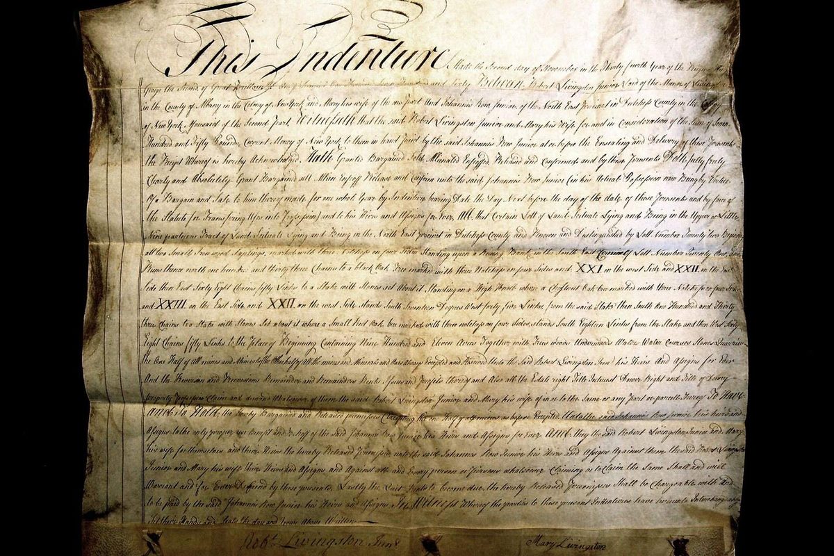 A signed property deed with a notary stamp lying on a desk, the document United States counties record as proof that a house changed hands