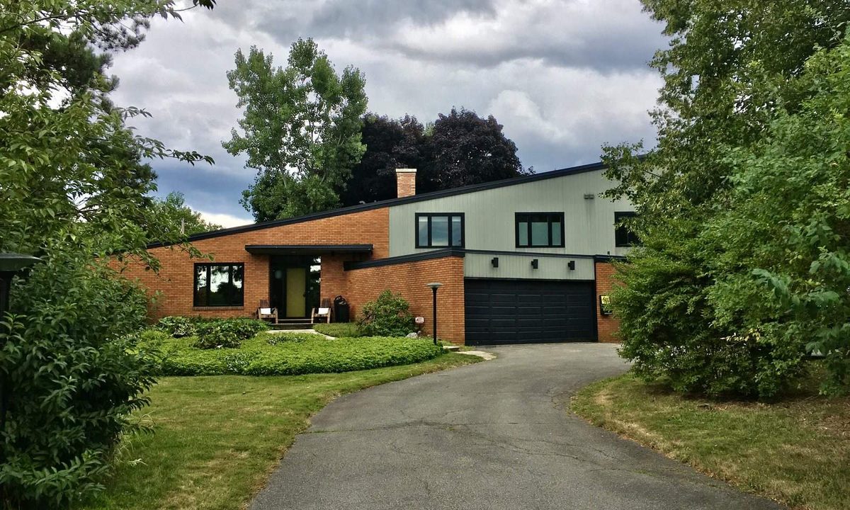 Three-bedroom suburban single-family house with a two-car garage, a mowed lawn and a For Rent sign at the curb