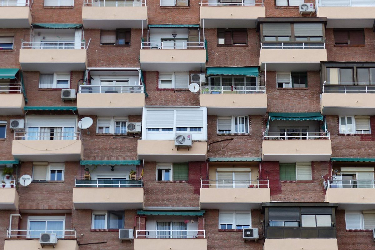 Fachada de un edificio de pisos con balcones en una calle de Madrid y un cartel de se alquila colgado en una ventana