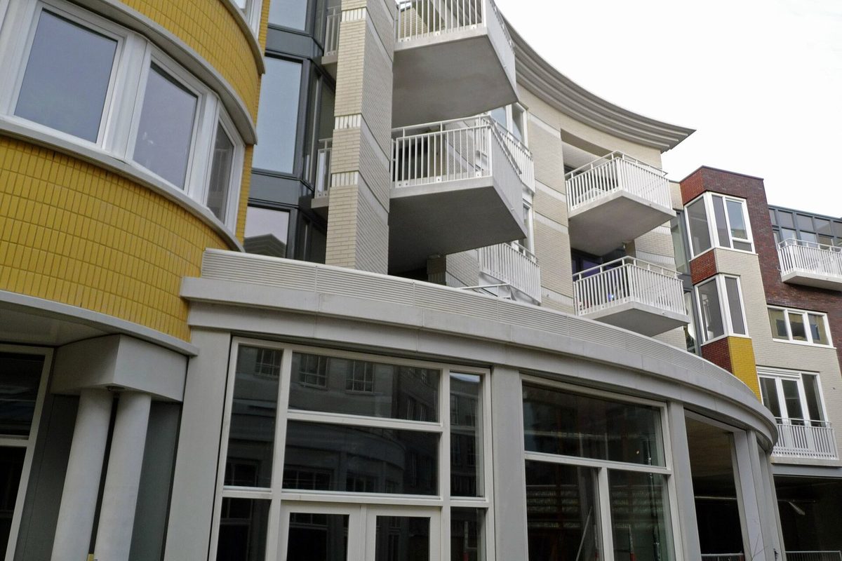 Immeuble d'habitation récemment livré avec balcons et panneau de commercialisation, illustrant la revente d'un appartement neuf