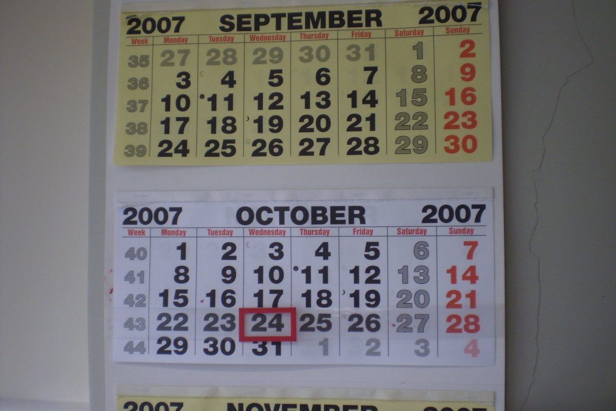 Calendario da parete accanto a un mazzo di chiavi e a una cartellina di documenti sul tavolo di una casa in vendita